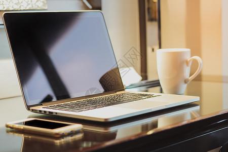 工作室服务台配备计算机膝上型电脑和智能手机咖啡杯在家工作概念图片