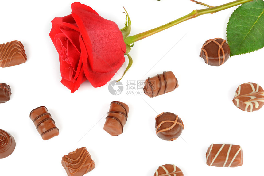各种巧克力糖果和红玫瑰孤立在白色背景上平坦的躺下最顶端视野图片