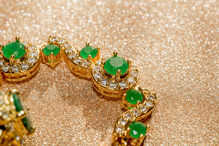 绿宝石金色戒指优雅的女首饰金手镯配有珍贵的绿宝石背景