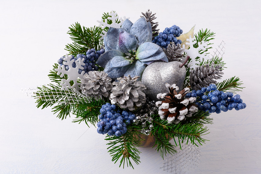圣誕綠色有银光亮的装饰品和蓝色丝绸薄荷与松锥和树枝的人工圣诞花朵配制圣誕桌中心图片