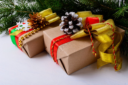 圣诞礼物是装饰雪和金松果的装饰品圣诞节背景和kraft纸包装礼品盒图片