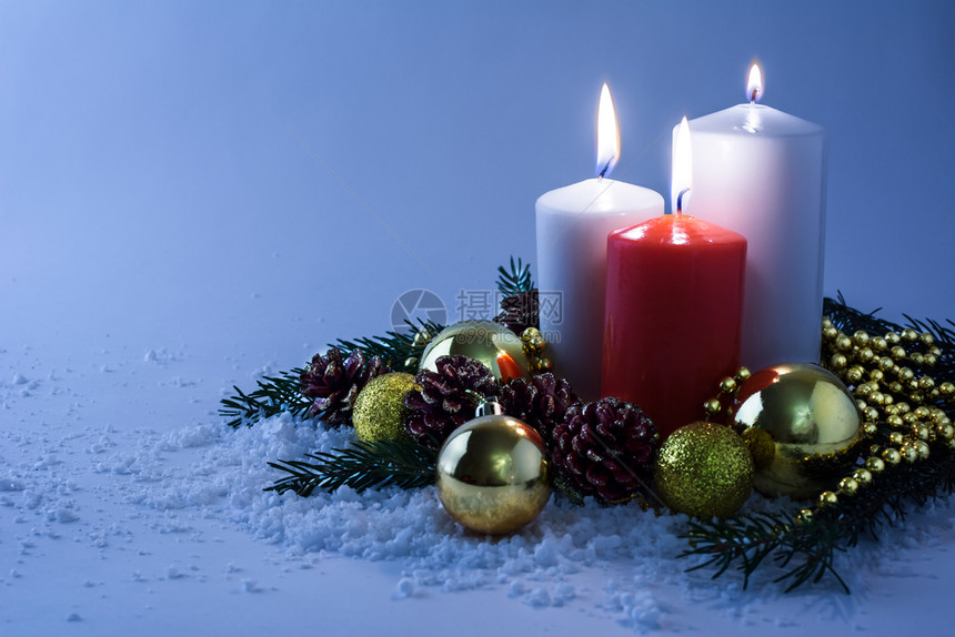 白色和红的圣诞蜡烛金球圆树枝和雪中的锥以浅蓝色背景在雪中发光图片