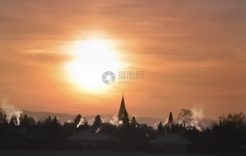 令人惊异的冬季风景与麻木的村庄吸烟囱和教堂塔色彩多的日出在十二月的清晨在德国图片
