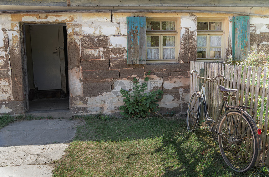 在shwabic大厅里在德国房子的外表下有敞开的门剥皮墙壁窗子有蓝色的木窗帘和一辆生锈的自行车图片