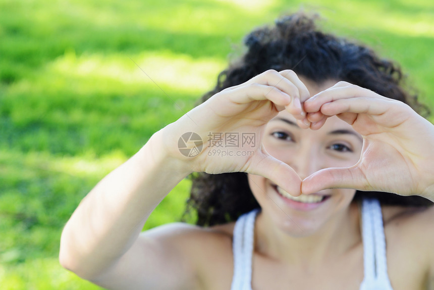 女手在绿色自然户外公园展示爱的象征年轻拉丁女孩图片