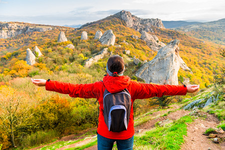 带着一个背包手空的女游客享受着山上秋天的风景图片