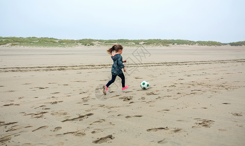 秋天在海滩上踢足球的小女孩在海滩上踢足球的小女孩图片