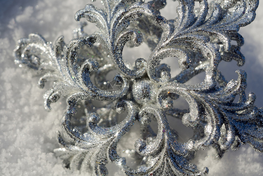 装饰银雪花闪发光亮于新鲜的白雪上图片
