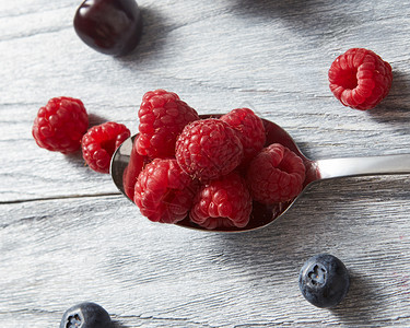 甜的果子放在灰色背景的汤匙上平坦素食理念大勺子红新鲜的草莓灰色背景的图片