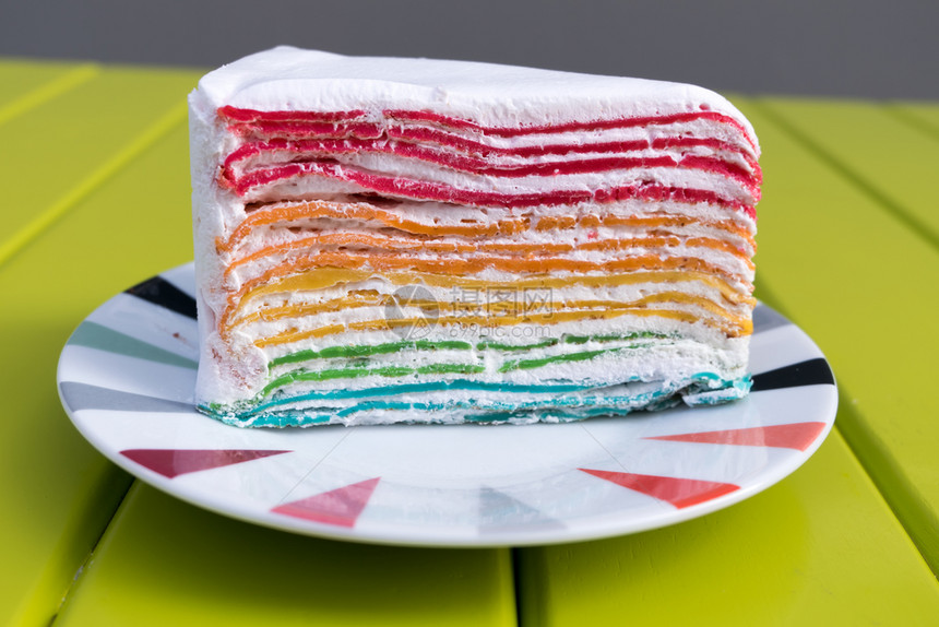 美味的彩虹蛋糕放在桌上的盘子图片