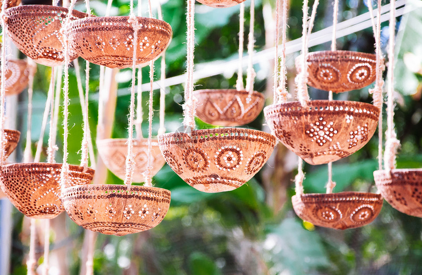 从吊在天花板上的椰子贝壳雕刻的装饰灯或植物锅图片