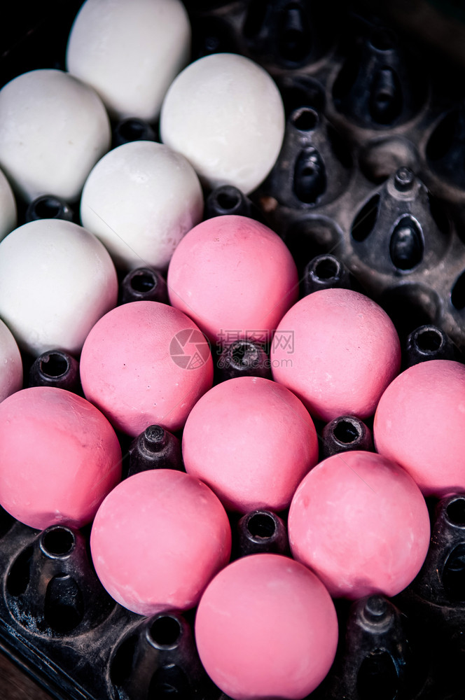 一大堆保存的粉红世纪鸡蛋和黑盘中的咸鸡蛋图片