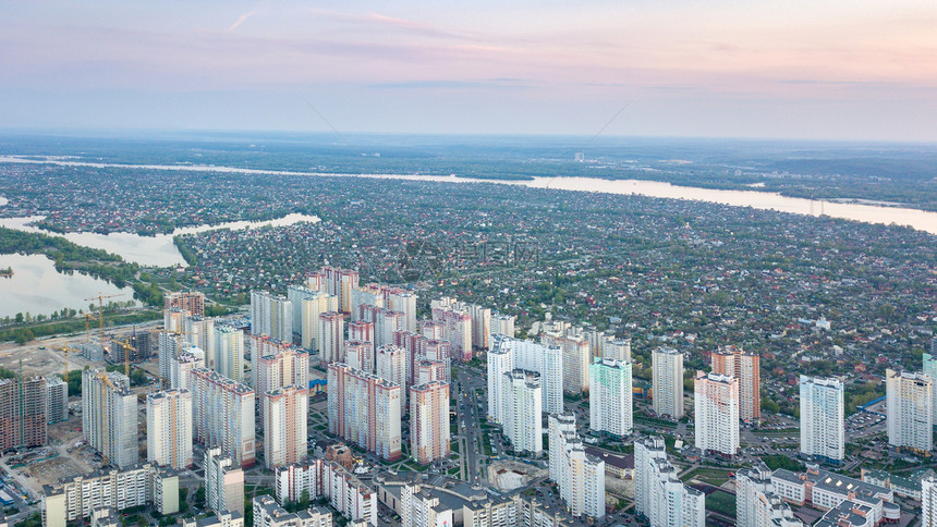该市左侧有私人住宅和新的高楼建筑物河日落时的基辅右侧乌克赖尼无人驾驶飞机照片基辅市全景与城的右侧和左以及日落时的德尼佩尔河图片