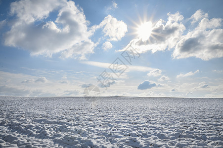 冬季风景一片空旷的草原覆盖在雪中地平线上与蓝天和白云相连阳光下德国图片