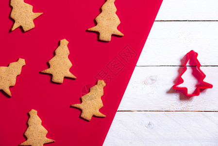 圣诞节用蜂蜜和姜汁饼干以红白背景的圣诞树和饼干切割机来烤最起码的基调图片