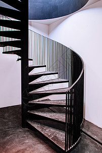 古老的螺旋楼梯有顶式混凝土地板黑毛色金属手栏和白墙图片