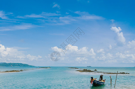 松鸣岩夏日在萨穆伊岛附近的高茶岩海滩泰河热带岛屿的长尾渔船蓝天沙乌伊岛背景
