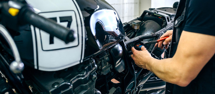 技工在车间更换保险丝修理定做的摩托车摩托车修理工换保险丝背景图片