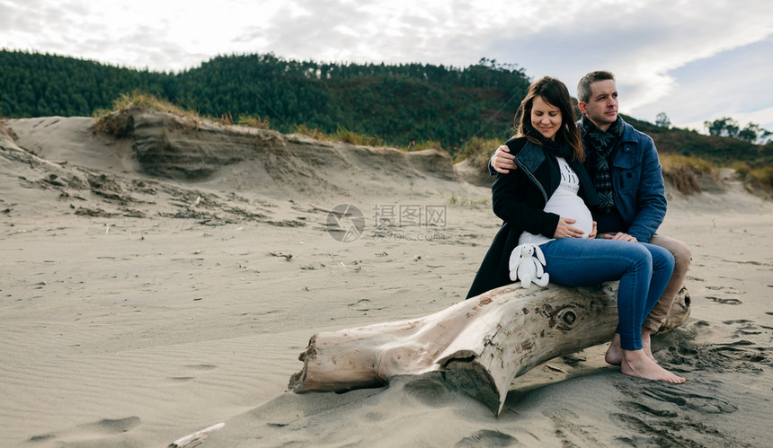 怀孕孕妇与她的伴侣海滩上图片