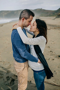 孕妇在沙滩上与伴侣拥抱图片