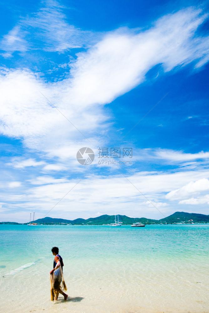 在热带岛屿海滩上行走的渔民图片
