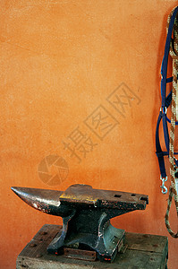 橙色混凝土墙上的旧金属铁板旧匠工具的详情图片