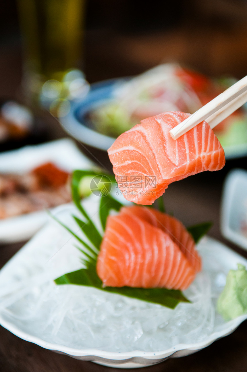 美的新鲜鲑鱼生片与筷子握在一起图片