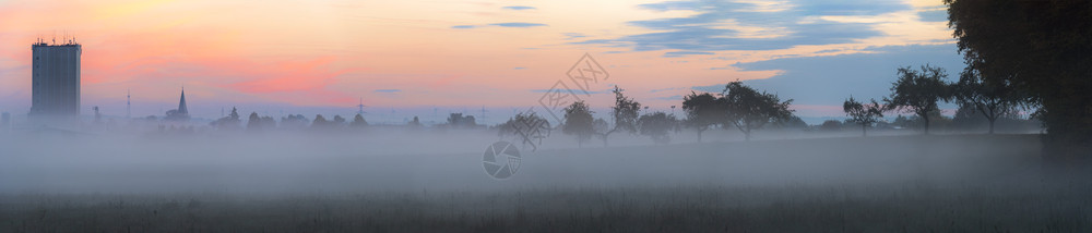 一片雾雨的秋天清晨一个德国村庄的轮廓一连串树木和森林边缘全都被雾笼罩图片