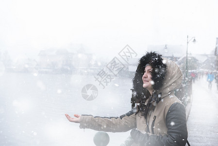 穿着冬夹克的年轻美女手伸抓住雪花享受的滋味图片