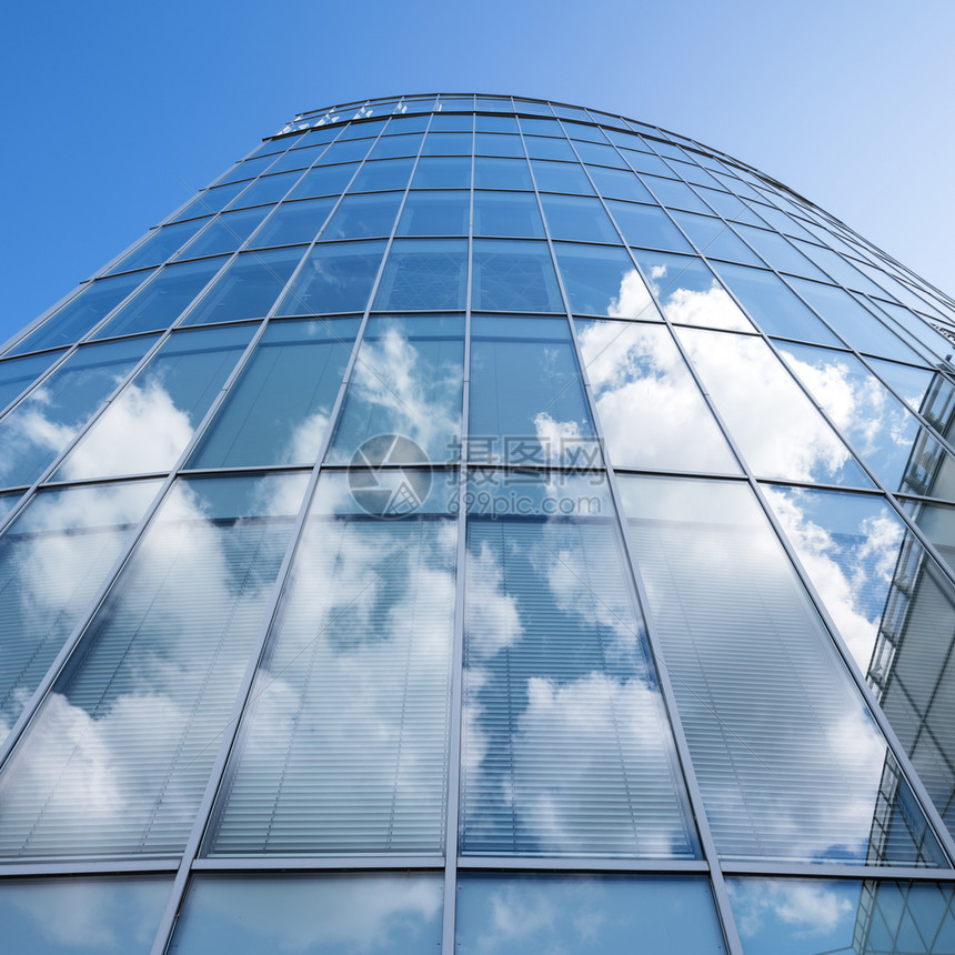 现代蓝玻璃和金属办公室建筑面罩反映云层和蓝天空图片