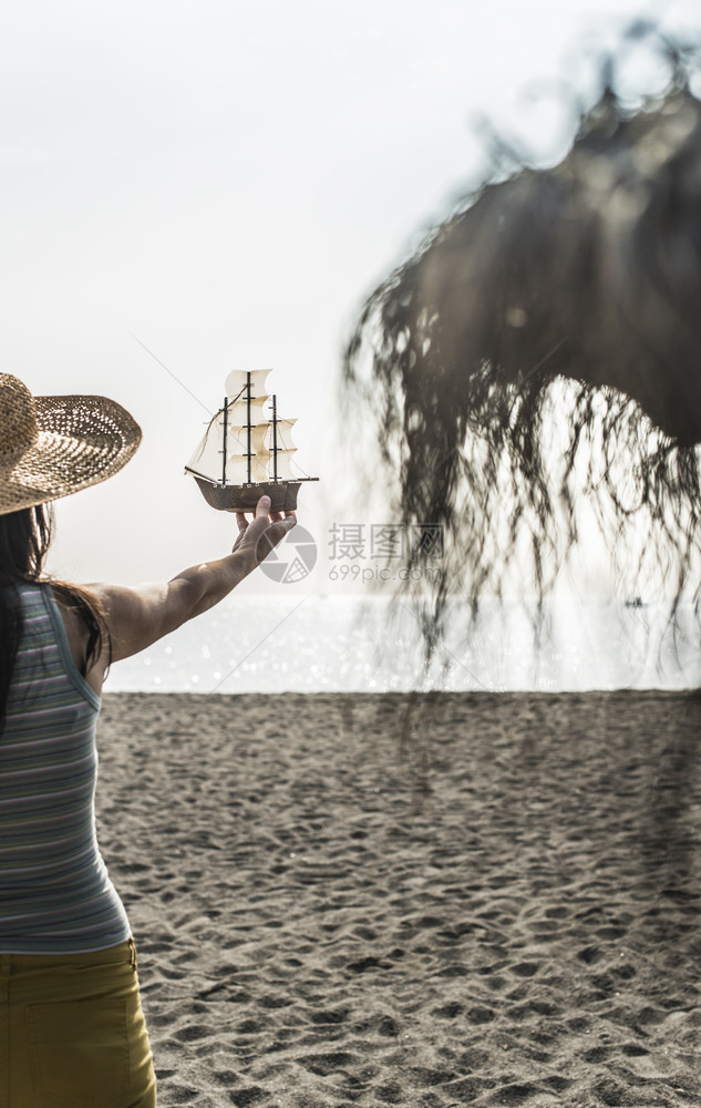模特举着帆船在海边拍照图片