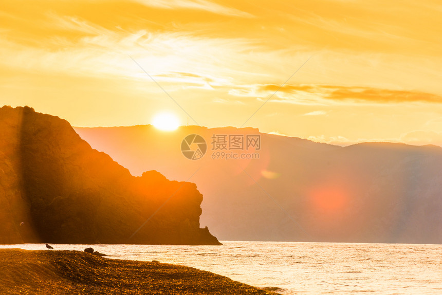 明亮的太阳美丽岩石和海洋黎明时美丽的风景图片