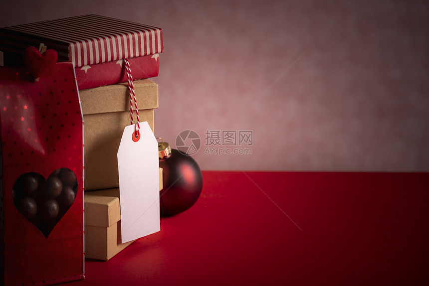 圣诞礼物主题图象上面有一堆礼物盒个红色糖果袋一个未写标签和红背景的xmas球图片