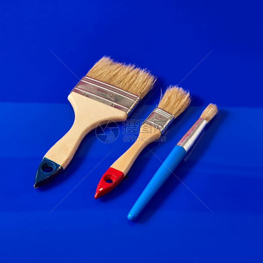用于公寓修理和完工的不同形状油漆刷子以蓝色背景与复制空间隔开一套用于油漆表面的刷子和蓝色背景的公寓修理图片