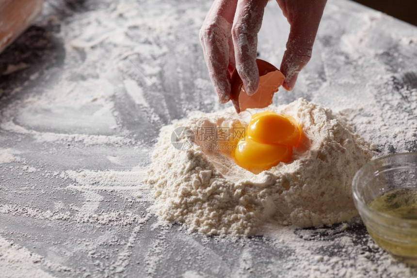往厨房桌上的面粉加入生鸡蛋图片