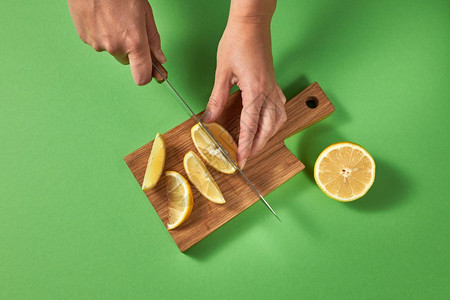 女用手切开一半熟的绿色柠檬并在的木板上用刀片切开图片