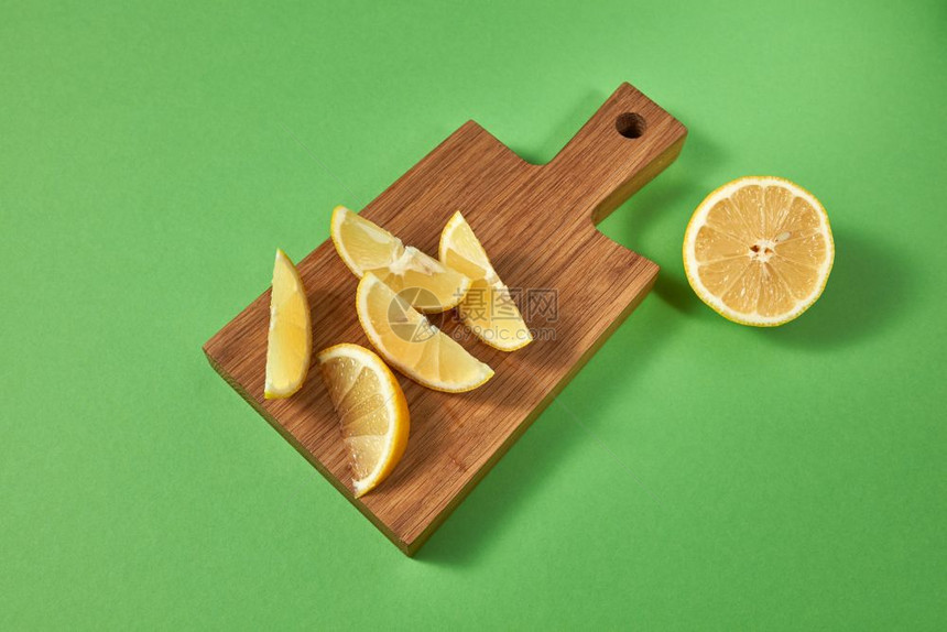 绿色背景的柑橘水果有文字位置用于在绿色木板上准备自制柠檬的天然黄片顶部视图一半和木制棕色板上的新鲜热带黄柠檬片上面的视图图片