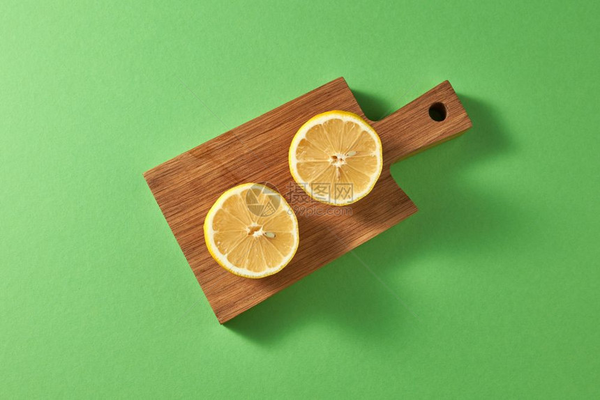 绿色背景和复制空间的柑橘水果木板上的黄天然柠檬顶部视图片烹饪夏季自制饮料的成分绿色背景的切木板上两块成熟的黄柠檬顶部视图图片