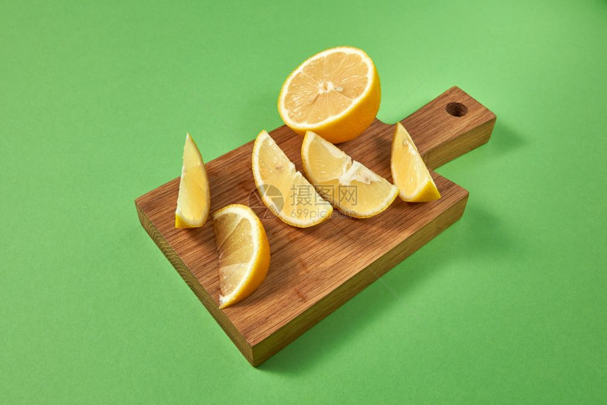准备天然饮食料的成分绿色背景的木制棕板上柑橘热带柠檬概念健康食物木制棕色板上的半份和片天然有机黄柠檬上面的视图绿色背景的多汁柑橘图片