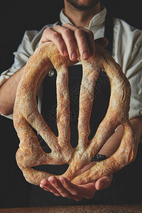 在黑暗的特写背景上面包师手里拿着面包面包师拿着福加斯面包图片