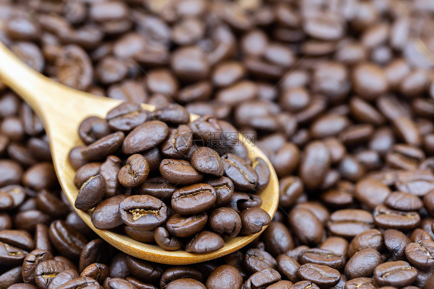 木勺上烤焦的棕色咖啡豆用于食品和饮料设计图片