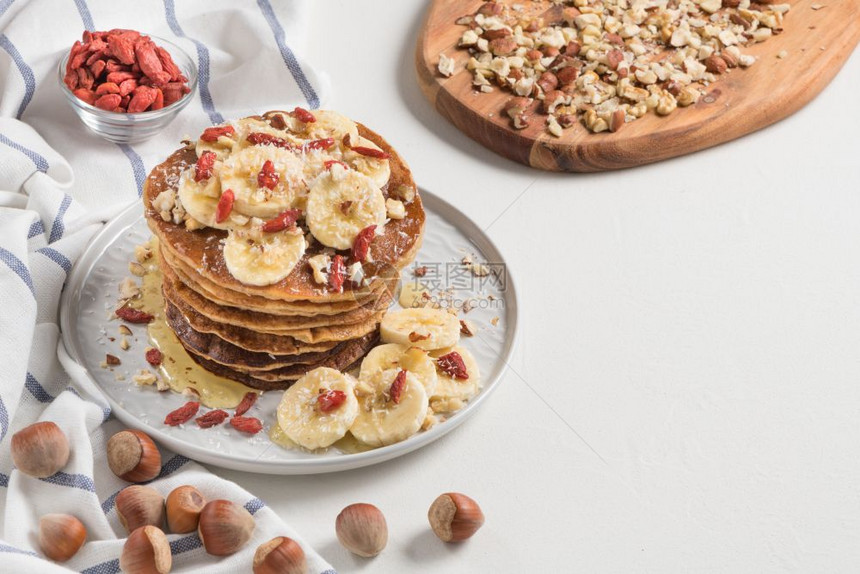 香蕉核桃果汁和蜂蜜的煎饼健康早餐白木桌底图片