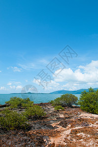 小岛屿上与背景中科托拉本岛相邻的科隆朗塔附近小岛上岩石沙滩绿灌丛图片
