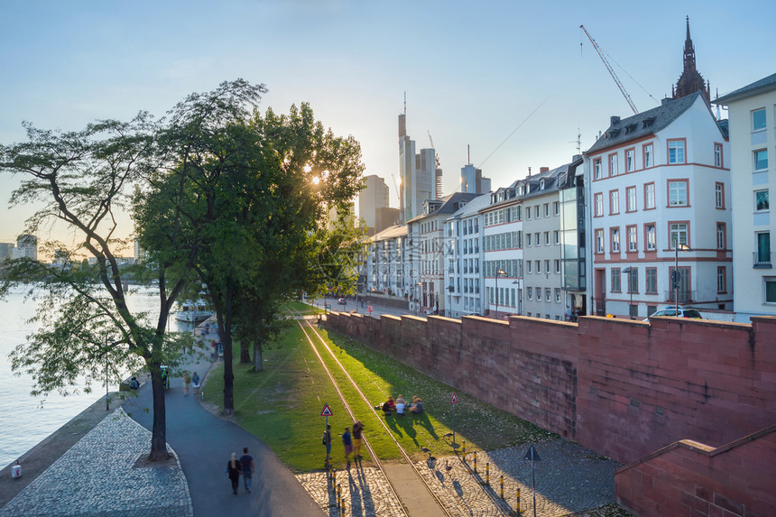 人们在城市堤防的绿草坪上行走和放松晚上阳光明亮棕褐色德国图片