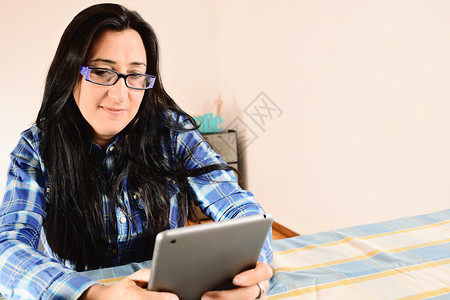 美貌中年女在家网上工作时使用平板电脑的肖像图片