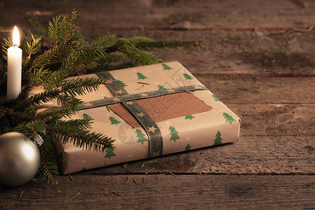 圣诞餐桌的装饰品包在古典棕色纸绿树枝圣诞舞会和蜡烛放在旧木桌上图片