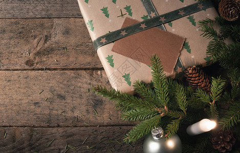 绿色树枝松果和圣诞球靠近古典棕色纸包着的礼物图片