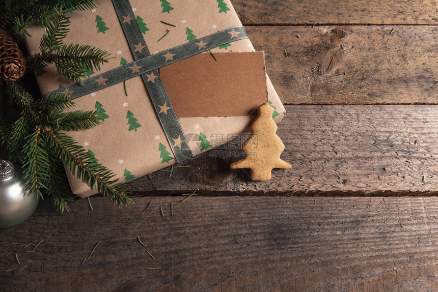 礼物包装在古典棕色纸和绿树设计枝圣诞形状的姜饼干和一张空白标签上图片
