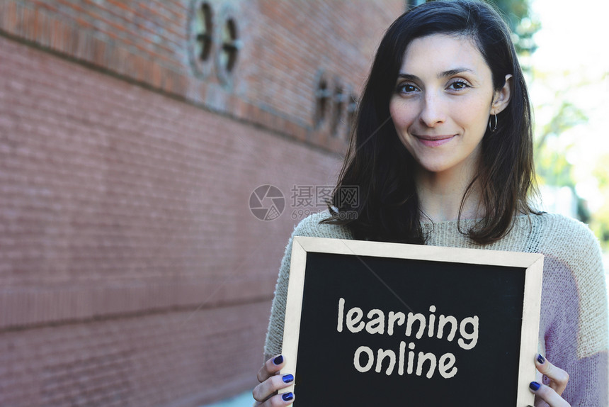年轻漂亮的女人拿着黑板用文字学习教育理念户外图片