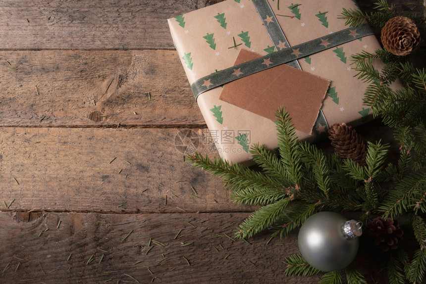 圣诞贺卡框有棕色礼物绿树周围是老桌子上的树枝松锥和xmas球图片